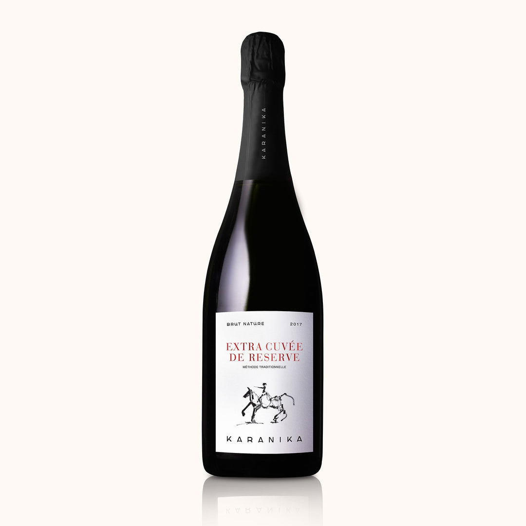 Domaine Karanika Extra Cuvee de Reserve 2017 Schaumwein in einer Flasche mit goldener Etikette auf einem Weinregal.